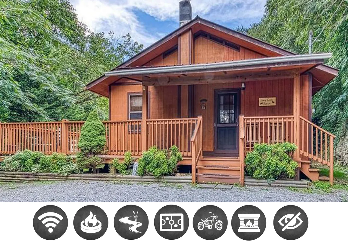 The image showcases the cozy exterior of a wooden cabin nestled in lush greenery, with a welcoming front porch featuring comfortable seating. The landscaped surroundings set a tranquil mood, while the porch offers the perfect spot to enjoy sunset views or morning coffee. The scene evokes relaxation and quality time, inviting guests to unwind and reconnect amid nature.