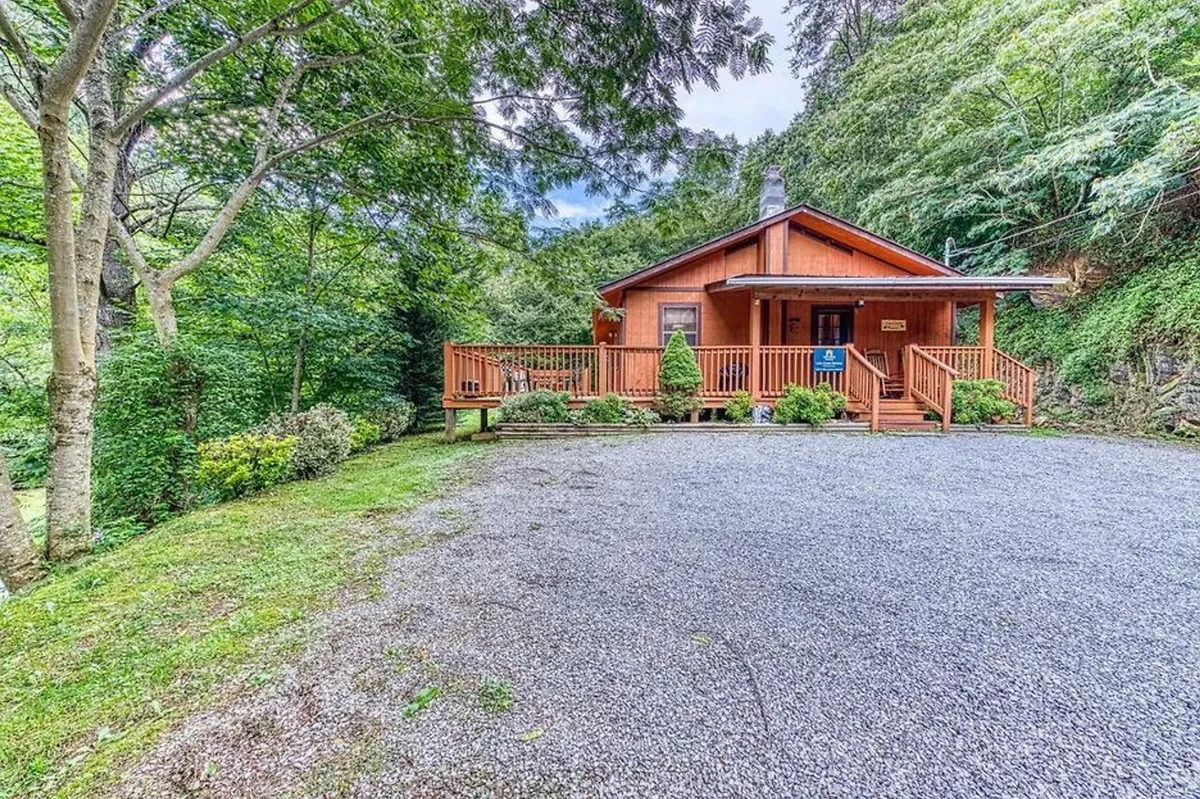This image displays the exterior of the wooden cabin, set amidst lush greenery, featuring a spacious deck. The scene conveys a sense of arrival and connection to nature, ideal for families preparing to set out on local adventures or unwind after a busy day. The setting emphasizes both the convenience of the location and the tranquility that awaits guests after their excursions.